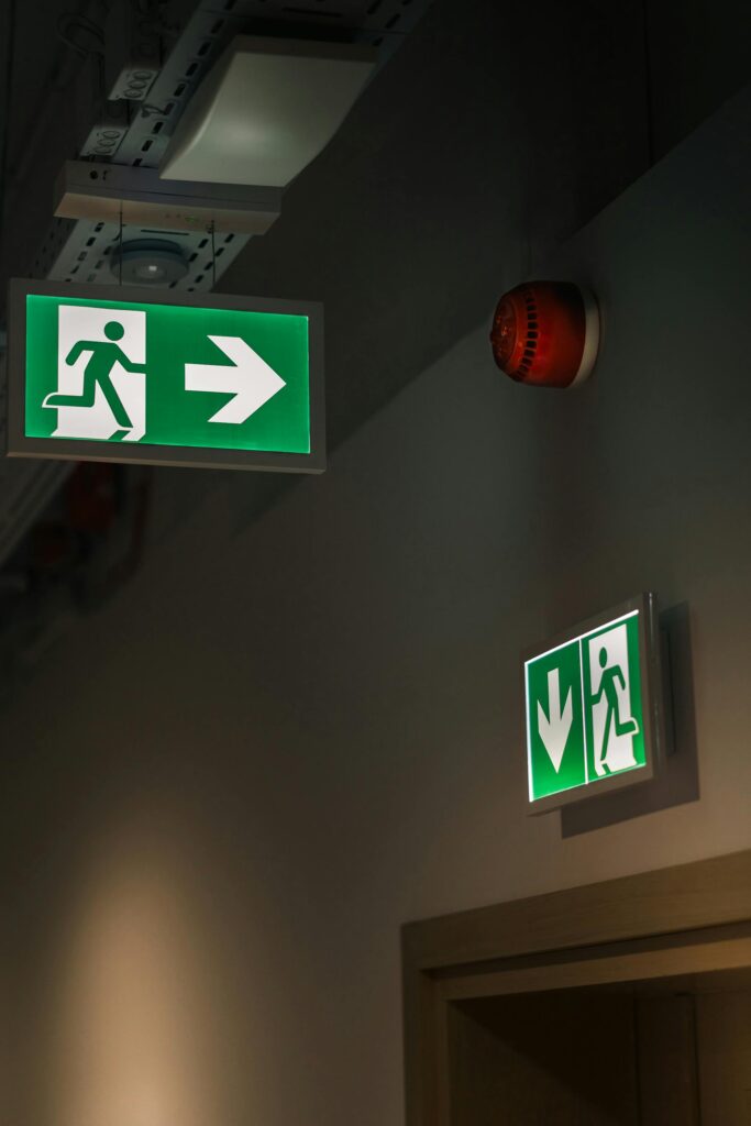 pexels-photo-29398063-29398063 Illuminated green emergency exit signs in a building hallway, ensuring safety and guidance.